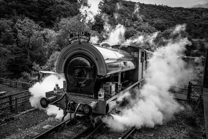 a steam engine on a train track with smoke coming out of it