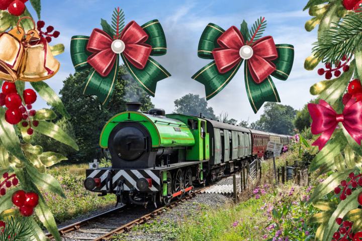 Green train on tracks surrounded by holiday-themed decorations and greenery.