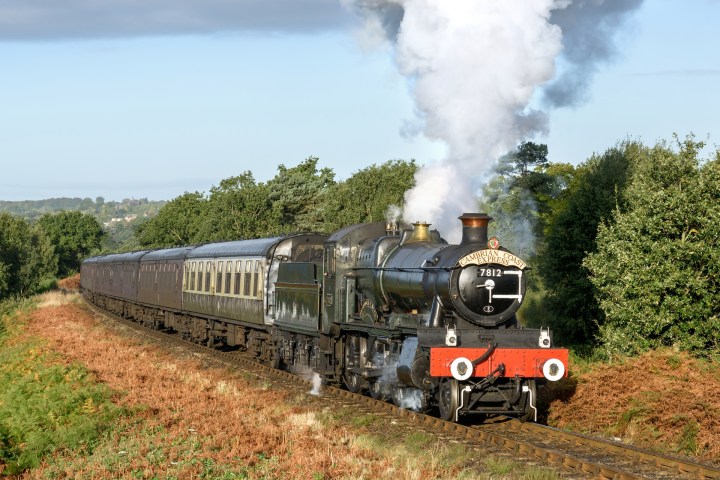 a steam engine riding on a train track with smoke coming out of it